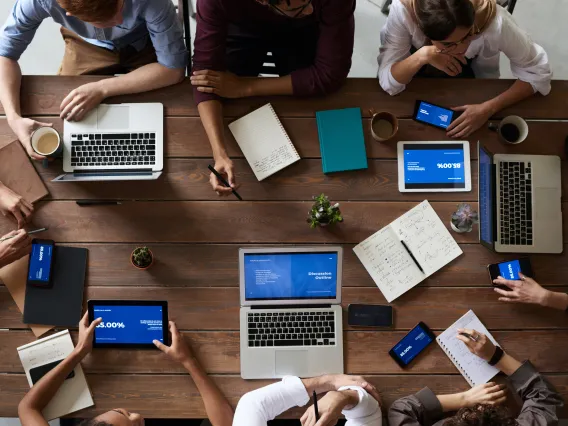 Bird's eye view of people meeting in a coffee shop with laptops.