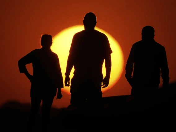 People watch the sunset from the Liberty Memorial grounds in Kansas City, Mo., May 12, 2025. (AP Photo/Charlie Riedel, File)