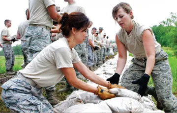 People working on a sand bag wall